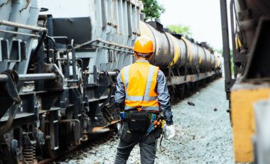 Başlık ve yelek giyen Müfettiş Mühendislik demiryolu inşaatını kontrol etmekten aranıyor. Asyalı işçiler koordine etmek için telsiz kullanıyor..