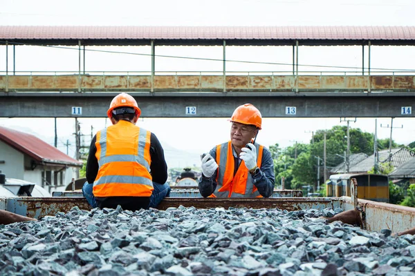 Inspector Engineering wearing helmet and vest worker unifrom checking railway construction work on rail track. Asian worker and coworker on rock wool bogie