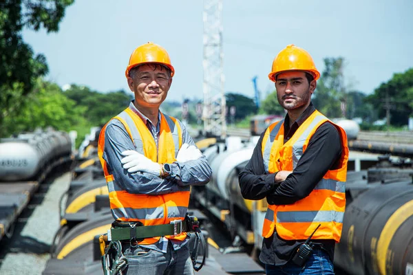 Inspector Engineering wearing helmet and vest worker unifrom checking railway construction work on rail track. Asian worker and coworker stand with their arms crossed and look at the camera.