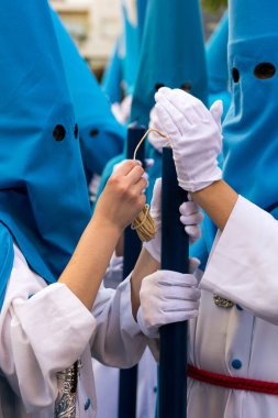 A penitent lights a candle during the Holy Week processions in Andalusia, Spain