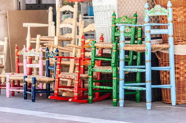 Several wood and wicker chairs in different colors