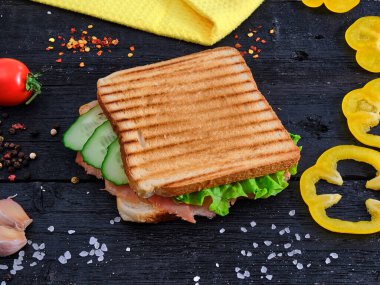 Sandwich on wooden table with spices