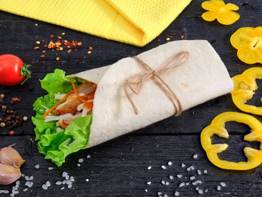 Tortilla wrap sandwich with meat and wegetables on table