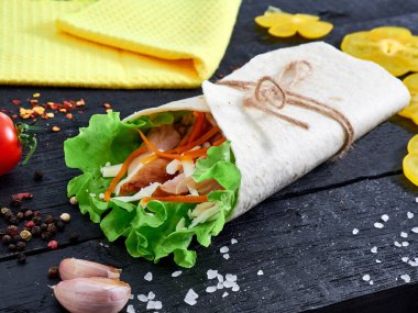 Tortilla wrap sandwich with meat and wegetables on table