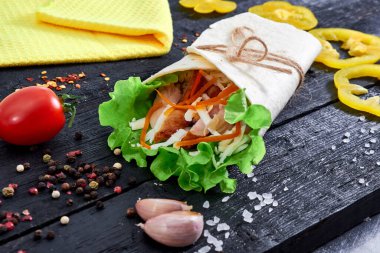 Tortilla wrap sandwich with meat and wegetables on table