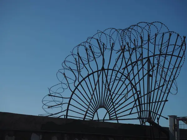 Dikenli tel, mavi gökyüzüne karşı güvenlik çitleriyle çevrili.
