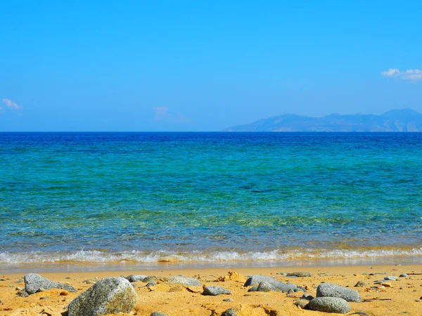 Sahildeki altın kum, sakin turkuaz Ege Denizi 'ne bakıyor.