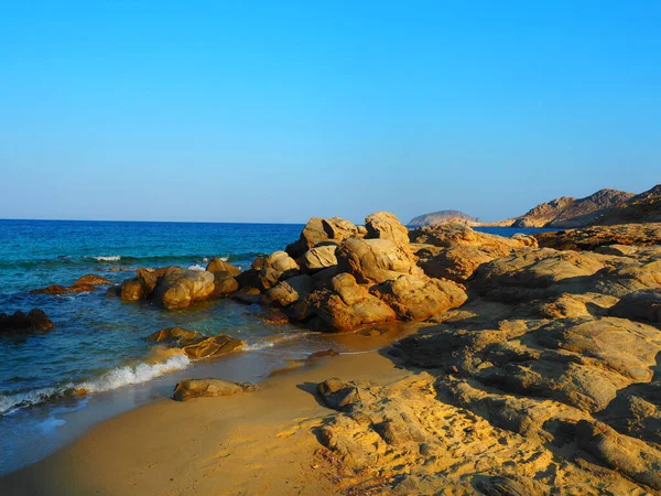 Yunanistan 'ın Serifos Adası' nda gün batımında parlayan kumlu sahildeki dramatik kaya oluşumları
