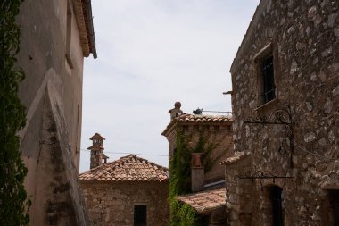Eze, Fransa - 17 Haziran 2021 - güneşli bir bahar öğleden sonra Fransız Rivierası tepelerinde bir ortaçağ kasabası - sokaklar ve antik köşelerinden oluşan labirentinde yürür.                               
