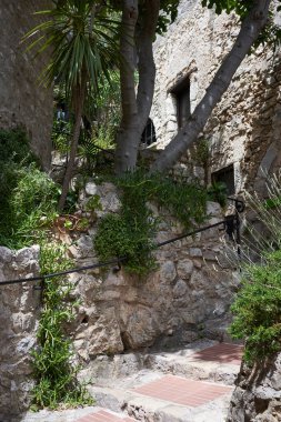 Eze, Fransa - 17 Haziran 2021 - güneşli bir bahar öğleden sonra Fransız Rivierası tepelerinde bir ortaçağ kasabası - sokaklar ve antik köşelerinden oluşan labirentinde yürür.                               