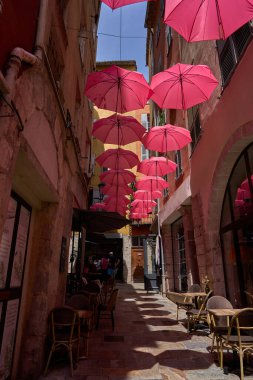  Grasse, Fransa - 12 Haziran 2025 - Pembe şemsiyeli bir Avrupa kasabasında büyüleyici bir ara sokak                              