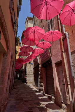  Grasse, Fransa - 12 Haziran 2025 - Pembe şemsiyeli bir Avrupa kasabasında büyüleyici bir ara sokak                              