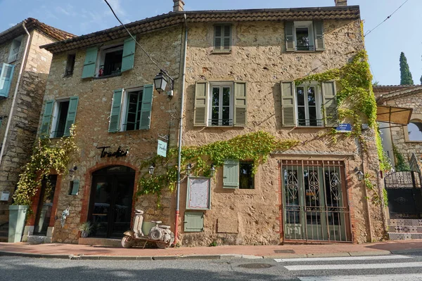 Valbonne, Fransa - 13 Haziran 2025 - Sarmaşıklı ve sessiz bir caddeye park edilmiş siyah arabalı hoş bir taş bina                           