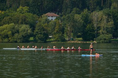 Brno, Çek Cumhuriyeti - 16 Ağustos 2025 - Brno Barajı - Kürek çekme ekipleri bir göl üzerinde kürek çekerken