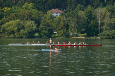 Brno, Çek Cumhuriyeti - 16 Ağustos 2025 - Brno Barajı - Kürek çekme ekipleri bir göl üzerinde kürek çekerken