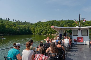 Brno, Çek Cumhuriyeti - 16 Ağustos 2025 - Brno Barajı - Turistler yemyeşil ormanlarla çevrili sakin bir barajda tekne turunun tadını çıkarıyorlar