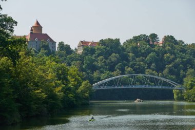 Brno, Çek Cumhuriyeti - 16 Ağustos 2025 - Brno Barajı - Modern kemer köprüsü, mavi gökyüzü altındaki yemyeşil ormanlarla çevrili