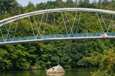 Brno, Çek Cumhuriyeti - 16 Ağustos 2025 - Brno Barajı - Modern kemer köprüsü, mavi gökyüzü altındaki yemyeşil ormanlarla çevrili