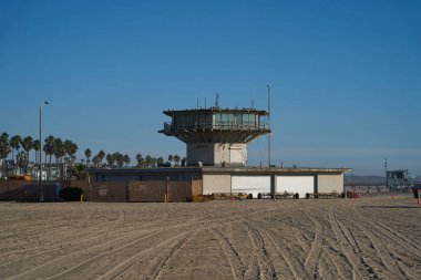 Los Angeles, ABD - 18 Ekim 2025 - Venedik Plajı - Cankurtaran kulesi ve kumlu bir sahilde açık mavi gökyüzü altındaki sahil binaları