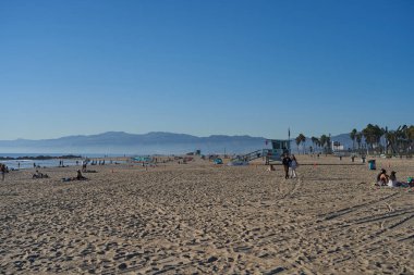 Los Angeles, ABD - 18 Ekim 2025 - Venedik Plajı - Cankurtaran kulesi ve kumlu bir sahilde açık mavi gökyüzü altındaki sahil binaları