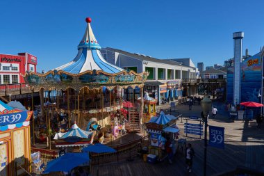 San Francisco, ABD - 27 Ekim 2025 San Francisco Limanı 'nda güneşli bir gün, atlıkarınca ve kalabalıklar sahilde eğleniyor.