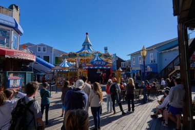 San Francisco, ABD - 27 Ekim 2025 San Francisco Limanı 'nda güneşli bir gün, atlıkarınca ve kalabalıklar sahilde eğleniyor.