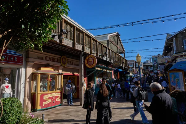 San Francisco, ABD - 27 Ekim 2025 - Rıhtım 39 'da güneşli bir gün. Turistler hareketli bir sahil boyunca dükkanlar ve restoranlarla geziyorlar.