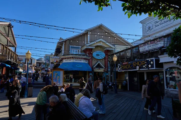 San Francisco, ABD - 27 Ekim 2025 - Rıhtım 39 'da güneşli bir gün. Turistler hareketli bir sahil boyunca dükkanlar ve restoranlarla geziyorlar.
