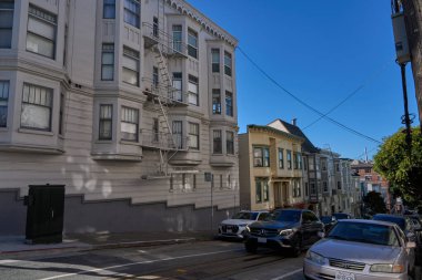 San Francisco, ABD - 28 Ekim 2025 - San Francisco Viktorya dönemi mimarisi dik bir tepede park etmiş arabalarla ve açık mavi gökyüzüyle