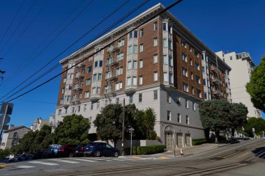 San Francisco, ABD - 28 Ekim 2025 - San Francisco Viktorya dönemi mimarisi dik bir tepede park etmiş arabalarla ve açık mavi gökyüzüyle