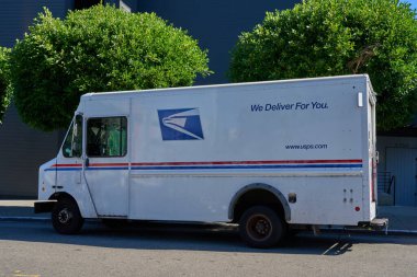 San Francisco, ABD - 28 Ekim 2025 - USPS posta kamyonu yeşil ağaçlar ve arka planda bina ile sokağa park edildi