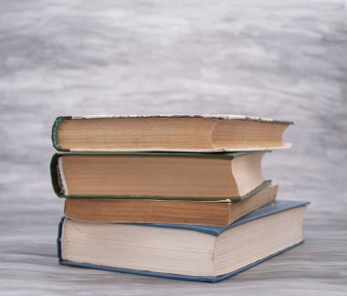 Gri arkaplan üzerine sarı sayfaları olan bir yığın eski kitap