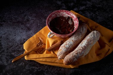 Osuruklar, İspanya, Valencia 'dan tipik hamur işleri, sıcak çikolatalı, Çin seramik kabında, sarı bir bezin üstünde, koyu bir yüzeyi var. Tatlı bir kahvaltı veya atıştırmalık..