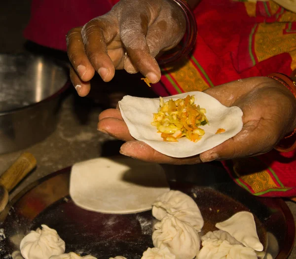 closeup of Indian Woman hands making purse shape dumpling momo ( cooking process )