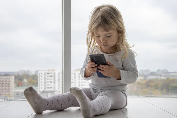 Ein Kleines Mädchen Sitzt Auf Dem Boden Vor Riesigen Fenstern — Stockfoto