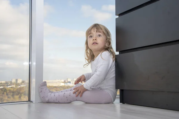小女孩坐在一个公寓的地板上 面对着巨大的窗户 城市的全景 儿童的孤独 梦想和观察 — 图库照片