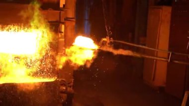 Metalürji uzmanı fırından maşayla sıcak metal bir çubuk çıkarıyor..