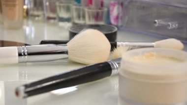 Bir kadının eli güzellik salonundaki masadan büyük bir makyaj fırçası alır..