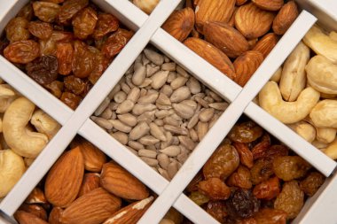 The box is divided into cashews, almonds, raisins and sunflower seeds, close-up, selective focus.