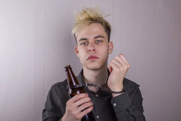 Nastolatek Kajdankach Butelką Ręku Szarym Tle Pojęcie Młodzieńczy Alkoholizm Wczesne — Zdjęcie stockowe