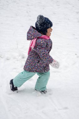 Portrait of a little girl running in the snow, blur in motion.