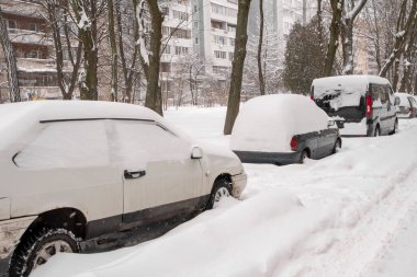 Park etmiş arabalar, karla kaplı, yol kenarında dururlar. Şehirde kar yağışı, düşen kar taneleri. Kavram: trafik çöküşü, artan yağış ve kar seviyesi, kar fırtınaları ve kar akıntıları.