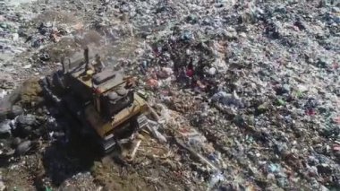 Açık şehir çöplüğü. Kuşlar uçuyor, buldozer atık yığınlarını düzleştiriyor, hava fotoğrafçılığı. Kavram: kentin çevre sorunları, çevre kirliliği, atık depolama alanı.