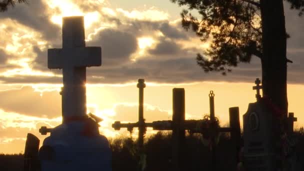 在乌云笼罩的夜空和夕阳西下的背景下 勾勒出古代石制十字架的轮廓 时间的流逝 埋葬在墓地 勾勒出死亡士兵的轮廓 — 图库视频影像