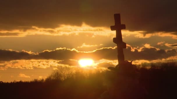 在乌云密布的夜空和夕阳西下的夕阳西下 一个古老的石头十字架的轮廓 葬在墓地 — 图库视频影像