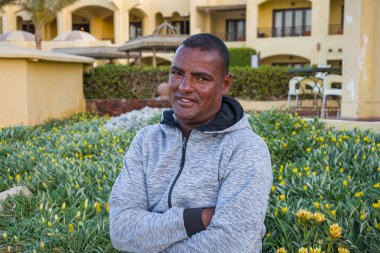 40 yıllık gülümseyen esmer tenli bir adamın portresi güzel binaların arka planında, yakın plan. Belki de cankurtaran ya da turist rehberi olarak çalışıyordur..