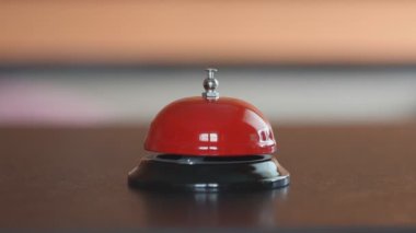Bir adamın eli ön masadaki zili çalar, yakın plan, bulanık arkaplan, seçici odaklanma. Danışmadaki resepsiyonisti arayın, otele ya da otele bir ziyaretçi.
