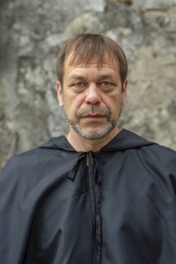 45-50 yaşlarındaki yaşlı bir keşişin portresi. Arka planda siyah bir bornoz takmış, doğrudan kameraya bakıyor. Kavram: lanet ve mistisizm, cadılık ve büyü.