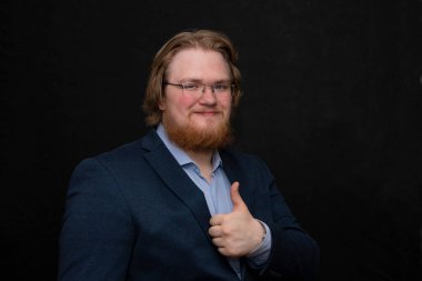 25-30 yaşlarında, pembe yanaklı, sakallı ve gözlüklü, gülümseyen şişman bir adamın stüdyo portresi..