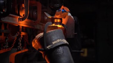 Bir çelik işçisi, çelik endüstrisindeki kalıplara erimiş metal döker. Taşıyıcı hareket eder..